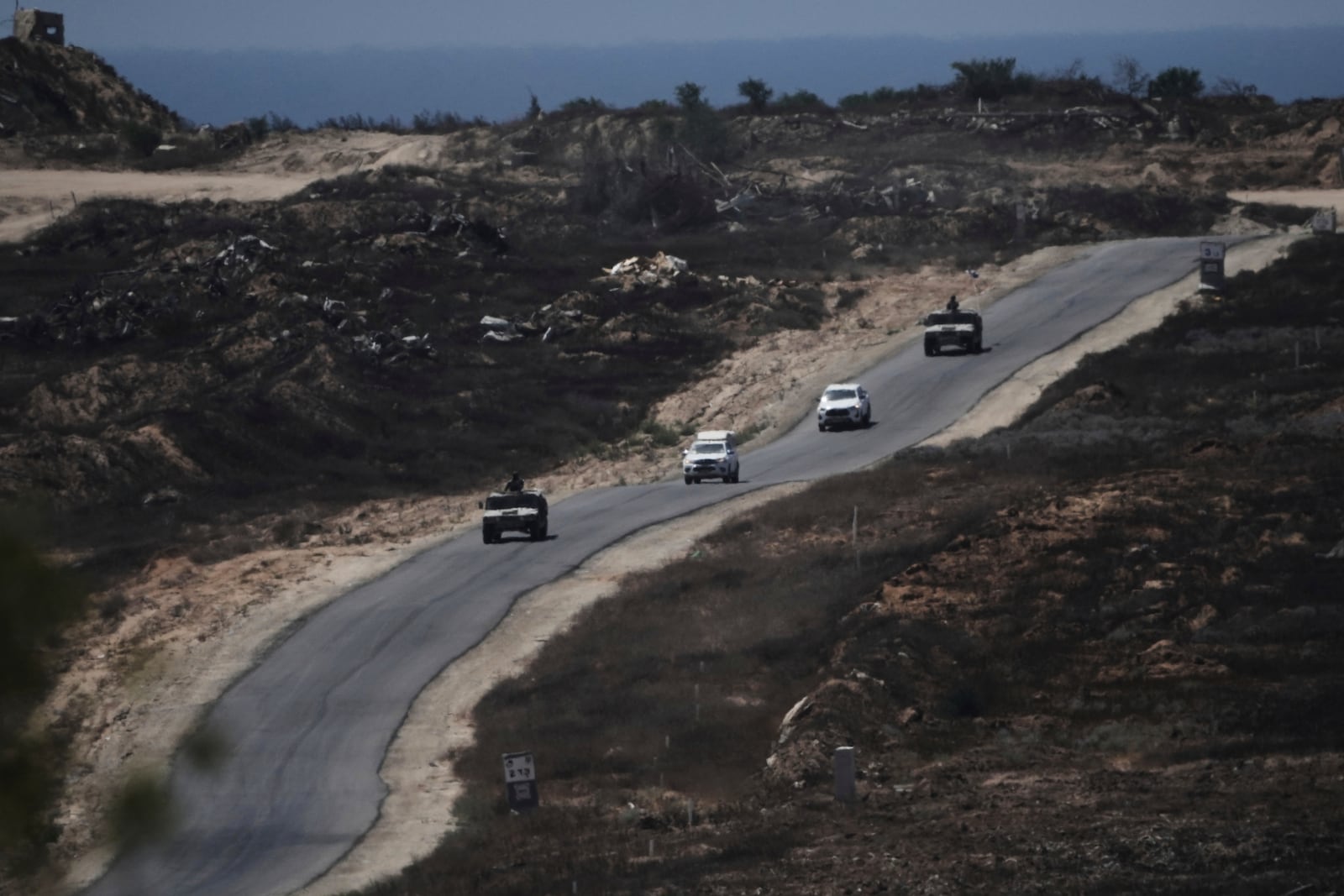 A convoy of Israel- military vehicles leaves the Gaza Strip near the Israel-Gaza border, seen from southern Israel, Monday, July 14, 2025. (AP Photo/Maya Alleruzzo)