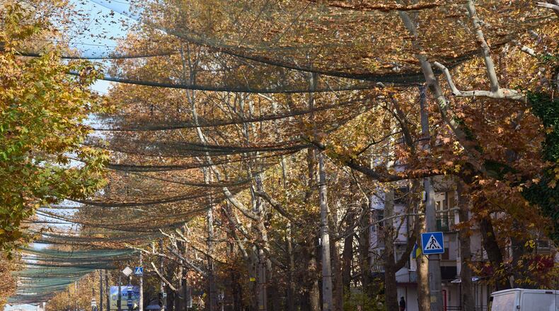 Local residents walk along the street covered with an anti-FPV-drone net in the frontline city of Kherson, Southern Ukraine, Monday, Nov. 3, 2025. (AP Photo/Efrem Lukatsky)