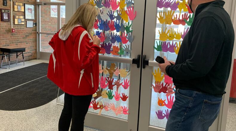 Fairfield West Elementary Principal Missy Muller was recently pleasantly shocked  when her school's nearly 800 students decorated the front lobby and office windows with paper cut outs of their hands adorned with emotional messages of support. Muller - left, reading some of the many messages - is battling a bone marrow disease and is leaving the city - and her job - temporarily for treatment. CONTRIBUTED