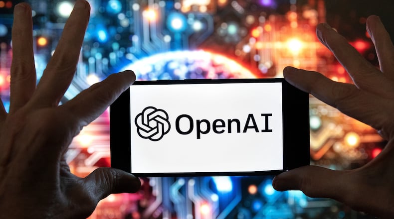 FILE - The OpenAI logo is seen displayed on a cell phone in front of an image on a computer screen generated by ChatGPT's Dall-E text-to-image model, Friday, Dec. 8, 2023, in Boston. (AP Photo/Michael Dwyer, file)