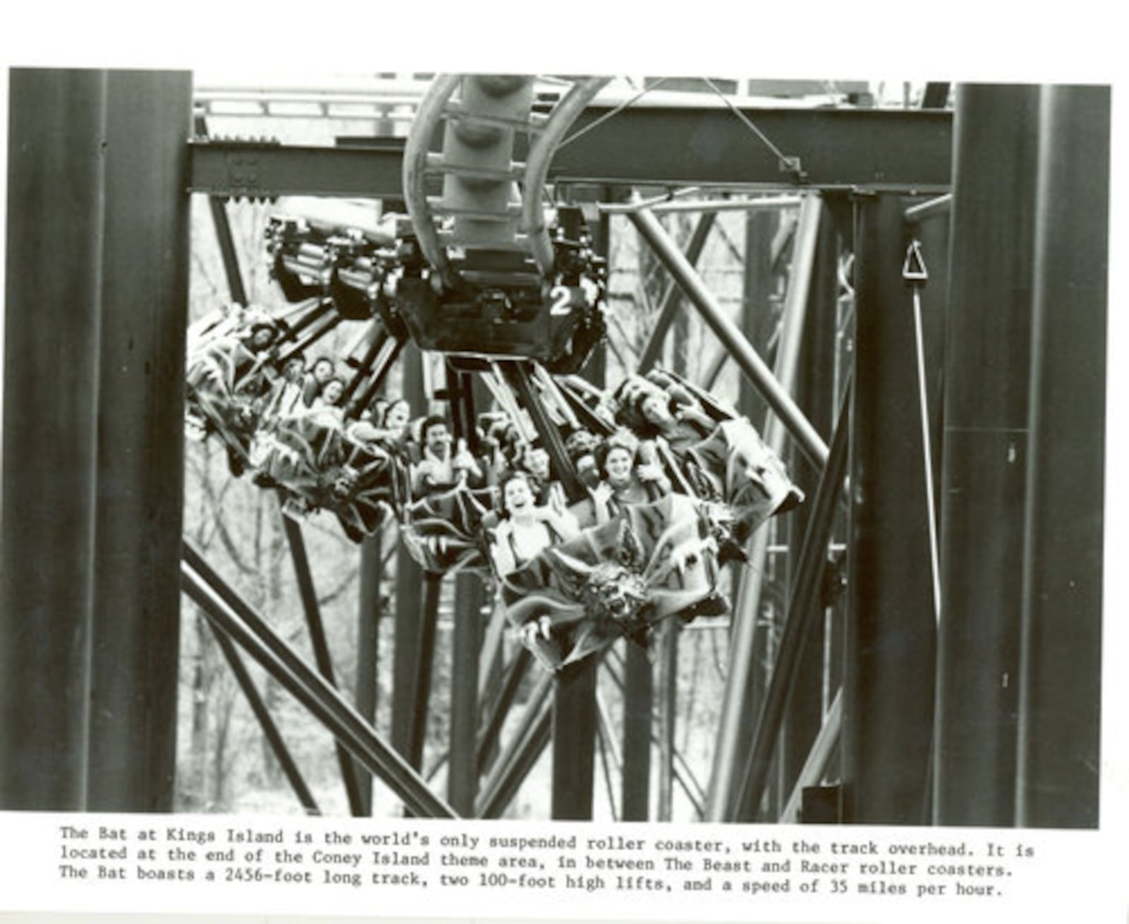 The short-lived Bat coaster in 1982. Caption reads: The Bat at Kings Island is the world's only suspended roller coaster, with the track overhead. It is located at the end of the Coney Island theme area, in between the Beast and Racer roller coasters. The Bat boasts a 2456-foot long track, two 100-foot high lifts, and a speed of 35 miles per hour."