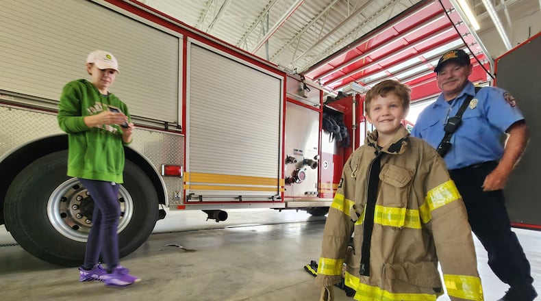 Lt. John Scranton shows off fire gear to Simon Morris, 5, and Rachel Morris during an open house for the new Middletown Division of Fire Station 82 on Ohio 122. NICK GRAHAM/STAFF