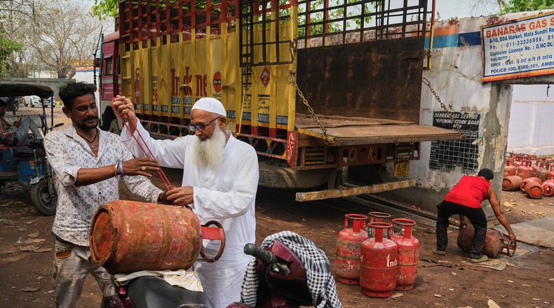 An elderly man ties a gas cylinder to his scooter after collecting it from a depot in New Delhi, Thursday, March 19, 2026. (AP Photo/Manish Swarup)