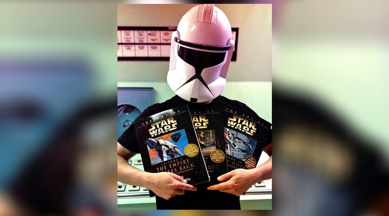 RiversEdge is launching a new family-friendly “Star Wars” movie night at 8:15 p.m. May 4 at 116 Dayton St., Hamilton. Pictured is Logan Walden in his Clone Trooper helmet holding up some Cosplay contest prize items donated from Unsung Salvage Design Company, in Hamilton. CONTRIBUTED