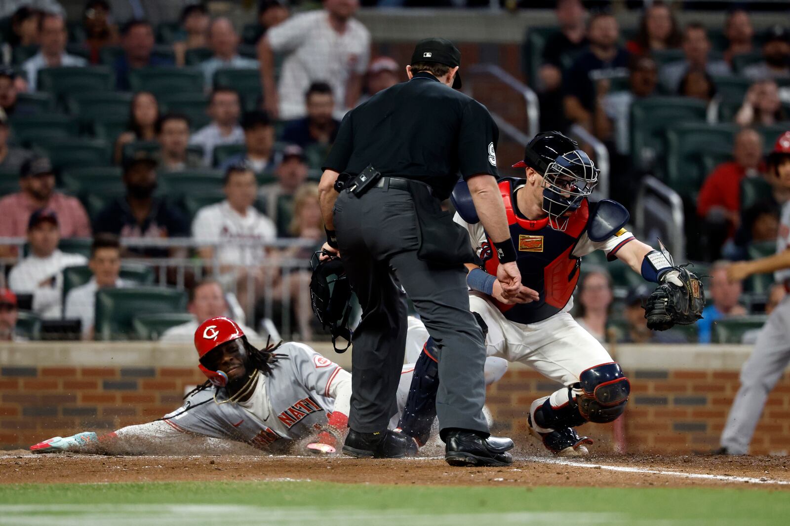 Cincinnati Reds' Elly De La Cruz (44) beats the throw to Atlanta Braves catcher Sean Murphy (12) as he slides safely into home plate during the eighth inning of a baseball game, Tuesday, May 6, 2025, in Atlanta. (AP Photo/Butch Dill)