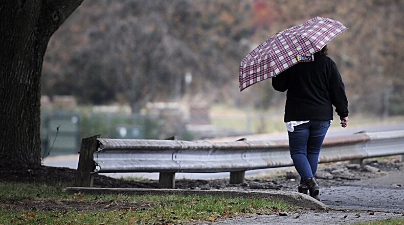 A woman walks in the rain near the University of Dayton campus area. MARSHALL GORBY/STAFF