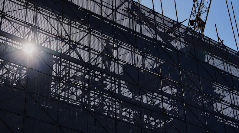 A worker installs scaffolding at a building under construction at the capital popular shopping district, in Beijing, Tuesday, Oct. 21, 2025. (AP Photo/Andy Wong)