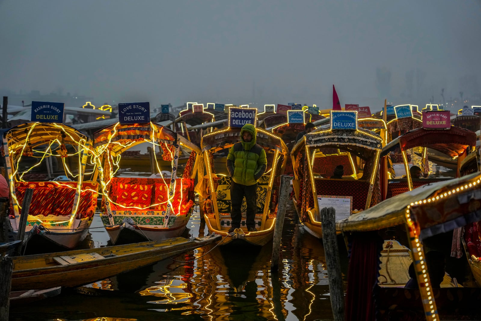 FILE - A Kashmiri boatman stands on his illuminated boat during a laser show and and live concert organized to boost winter tourism in Srinagar, Indian controlled Kashmir, Dec. 7, 2022. (AP Photo/Mukhtar Khan, File)