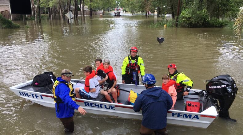 Members of Ohio Task Force 1 evacuates people from an apartment complex who were trapped by rising waters in the Houston area on Tuesday. Many of the Kettering-based task force s members are from southwest Ohio. CHUCK HAMLIN/STAFF
