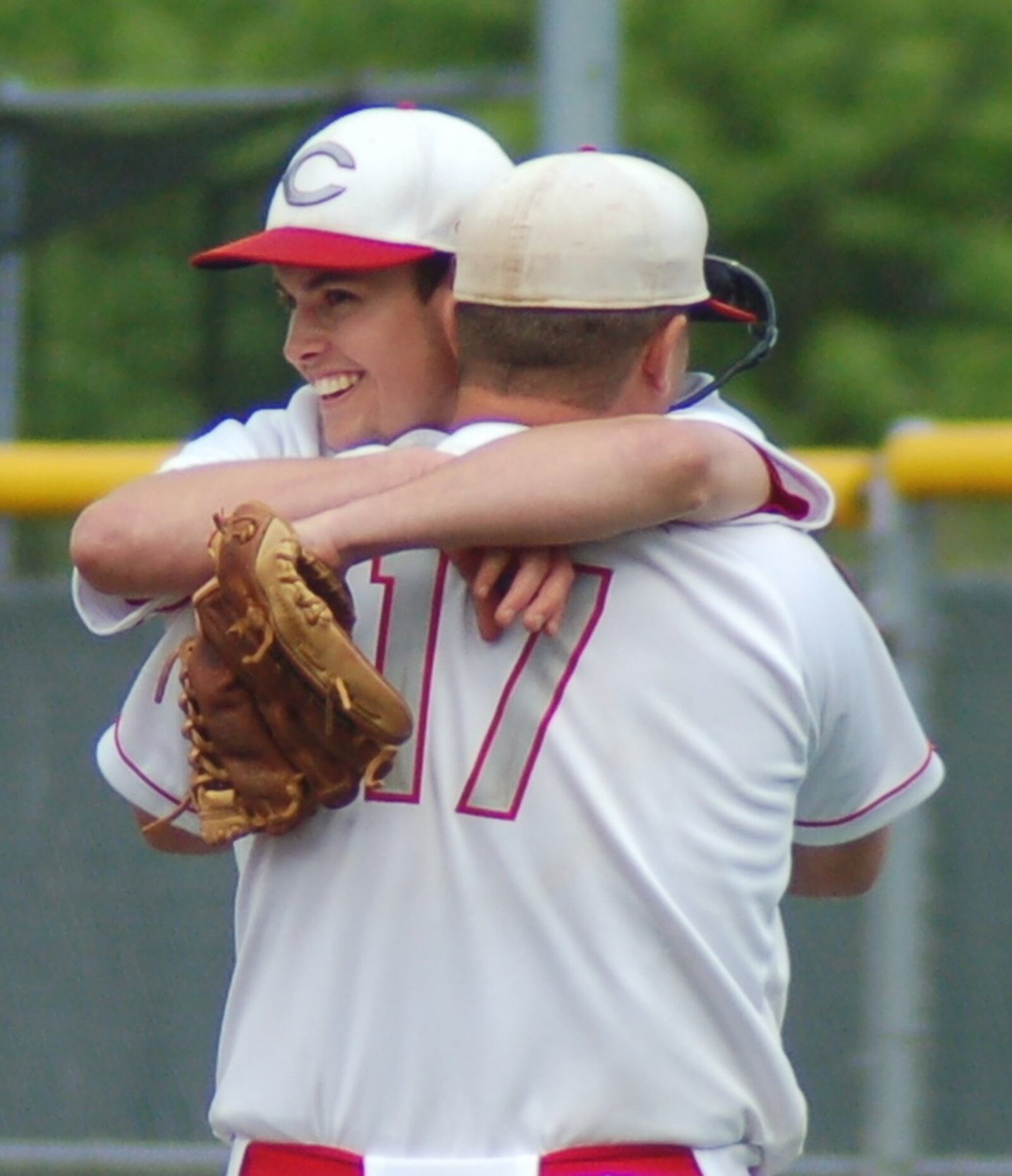 Carlisle pitcher Adam Goodpaster embraces teammate Jake Glover (17) on Thursday after their 2-0 win over Cincinnati Country Day in a Division III regional semifinal at the Athletes in Action complex in Xenia. CONTRIBUTED PHOTO BY JOHN CUMMINGS