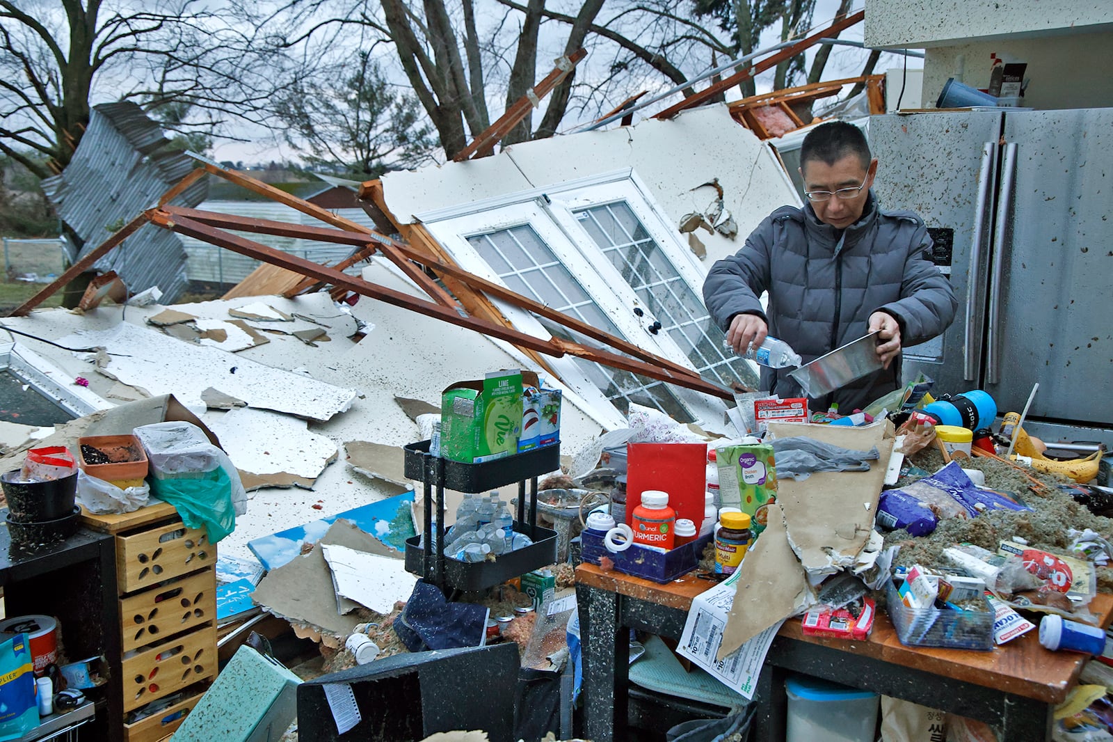Shoji Uota pours his dog some fresh water after finding the bowl in the debris of his kitchen after a Feb. 28, 2024 tornado destroyed his house on Ridge Road in Clark County. BILL LACKEY/STAFF
