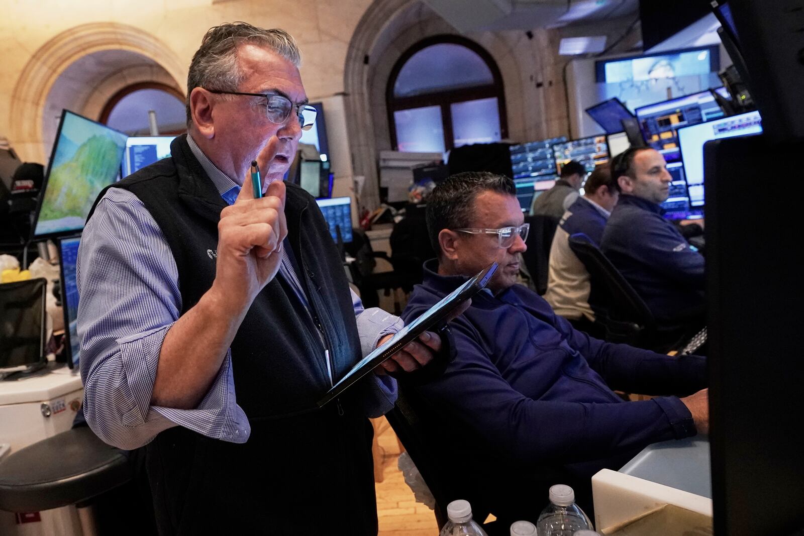 Trader John Bishop, left, works with colleagues on the floor of the New York Stock Exchange, Monday, April 21, 2025. (AP Photo/Richard Drew)
