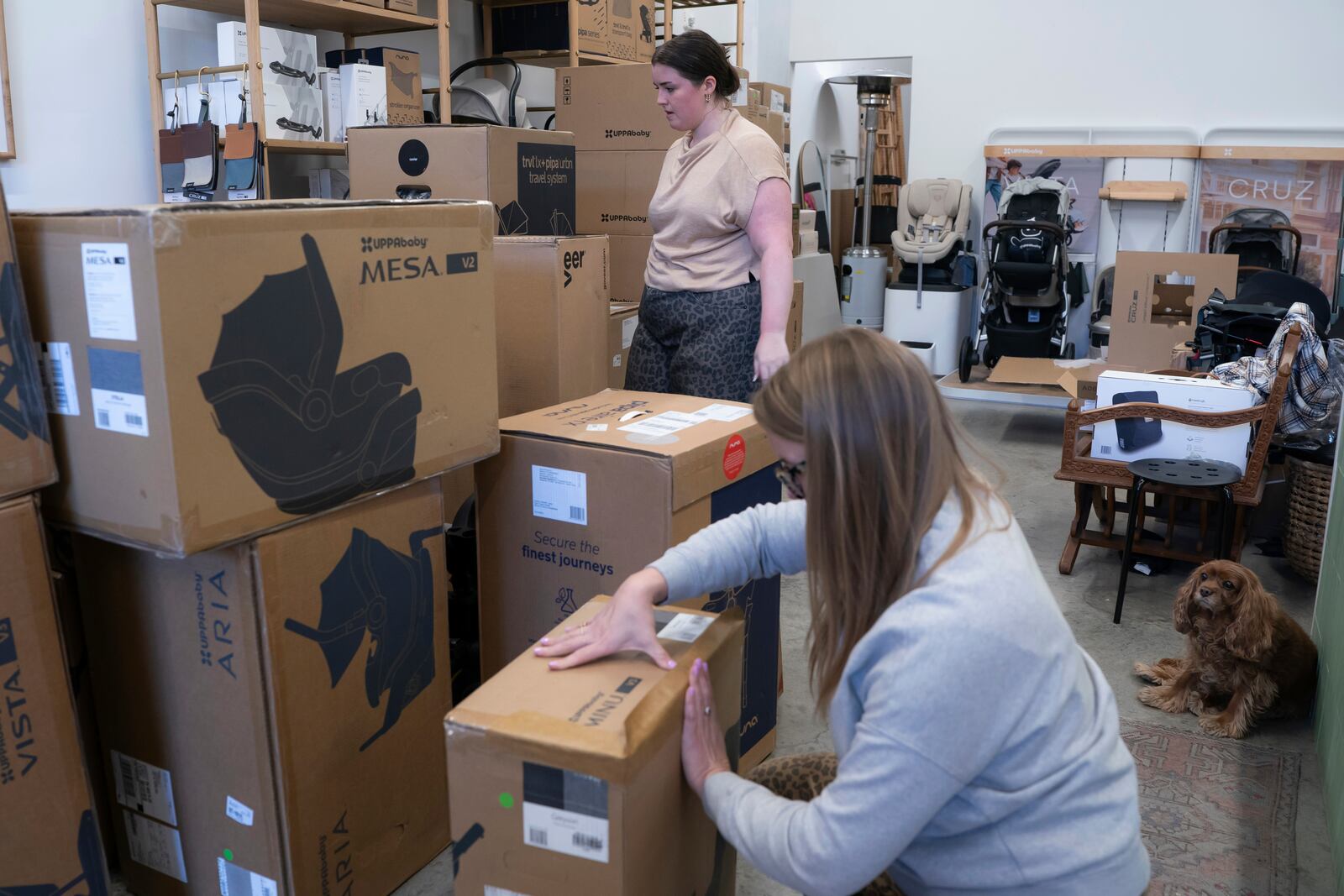 Elizabeth Mahon, owner of the baby store Three Littles, and sales associate Charlotte Santoli unpack strollers and other inventory ordered by customers ahead of tariff-driven price increases at the Union Market location in Washington, on Wednesday, April 16, 2025. (AP Photo/Nathan Howard)