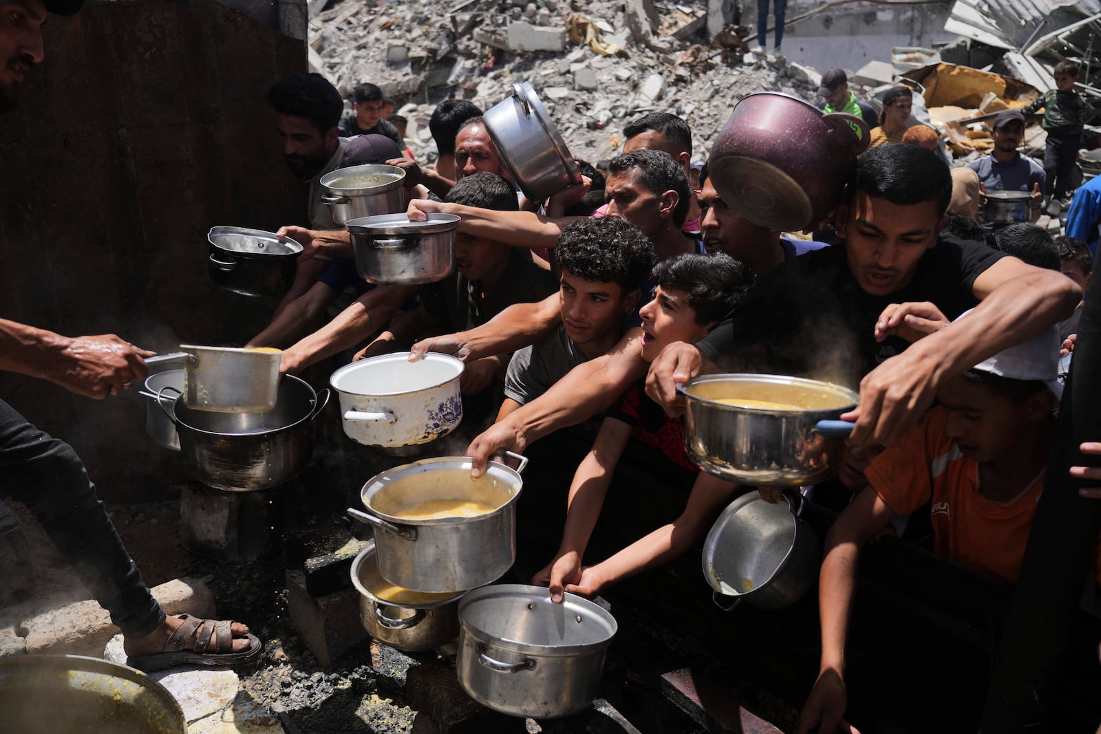 Palestinians struggle to get donated food at a community kitchen in Jabalia, northern Gaza Strip, Monday, May 19, 2025. (AP Photo/Jehad Alshrafi)