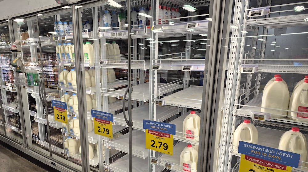 The milk shelves at the Springboro Kroger were empty Thursday and people stocked up before Saturday's forecasted large snow storm. Michael Kurtz / Staff