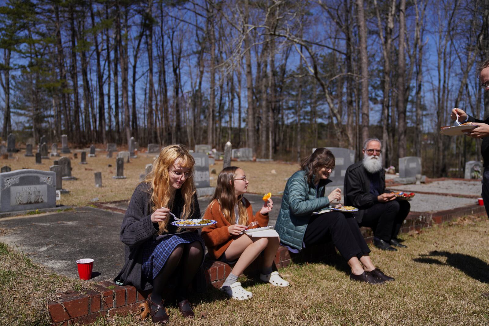 Sacred Harp singers sit among the headstones at Holly Springs Primitive Baptist Church for a midday potluck in Bremen, Ga., on Saturday, March 22, 2025. (AP Photo/Jessie Wardarski)