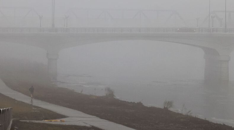 A person jogs on the bike path along the Great Miami River near the High-Main Bridge. Morning fog decreased visibility Wednesday morning, Jan. 24, 2024 in Hamilton. NICK GRAHAM/STAFF