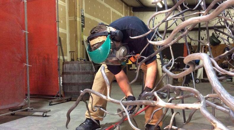 Kristin Kieffer, a Hamilton resident, works on grinding steel tree branches at Blue Hell Studio. CONTRIBUTED