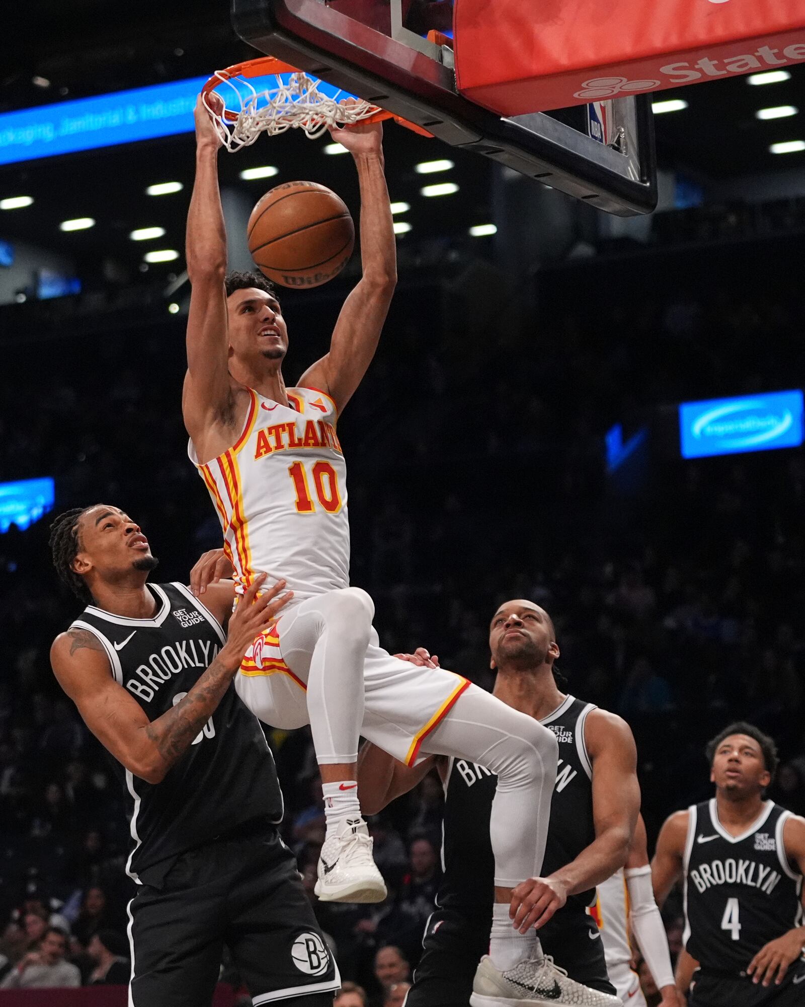Atlanta Hawks' Zaccharie Risacher (10) dunks the ball in front of Brooklyn Nets' Nic Claxton (33) and Tosan Evbuomwan (12) during the first half of an NBA basketball game Thursday, April 10, 2025, in New York. (AP Photo/Frank Franklin II)