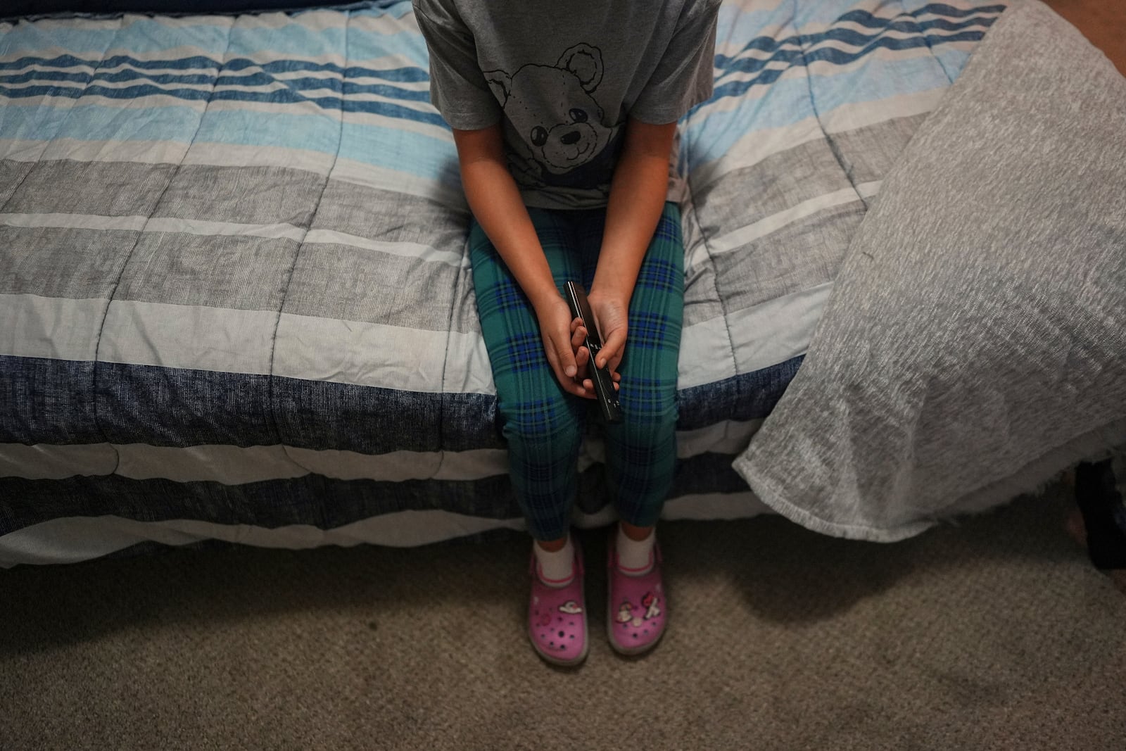 FILE - A 9-year-old girl with Temporary Protected Status, or TPS, who was born in Venezuela, but who fluently speaks only English and is in the gifted program at her school, watches TV in her family's apartment, April 5, 2025, in Doral, Fla. (AP Photo/Rebecca Blackwell, File)