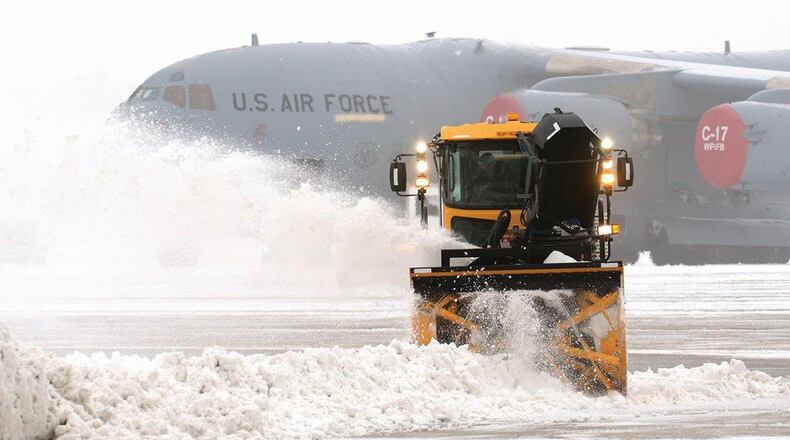 Snow surrounding a 445th Airlift Wing C-17 Globemaster III sitting on the ramp is removed as temperatures drop and fog rolls in during a 2014 winter storm at Wright Patterson Air Force Base. (U.S. Air Force photo/Tech. Sgt. Frank Oliver)
