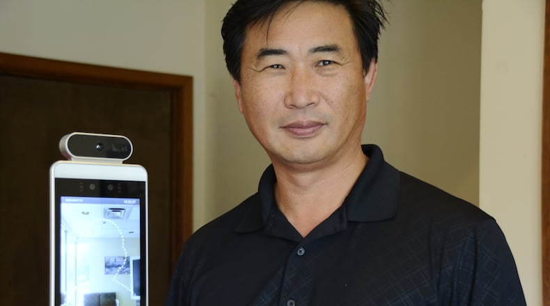CKS Solutions owner Peter Snug stands next to the SmartPass product, which is a temperature reading and facial nonrecognition device. MICHAEL D. PITMAN/STAFF
