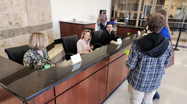 Hamilton employees Brooke Wells, left,  Jessica Harp, middle, and Jacob Stone-Welch help answer questions at Hamilton’s new customer service desk located at 345 High Street. NICK GRAHAM/STAFF