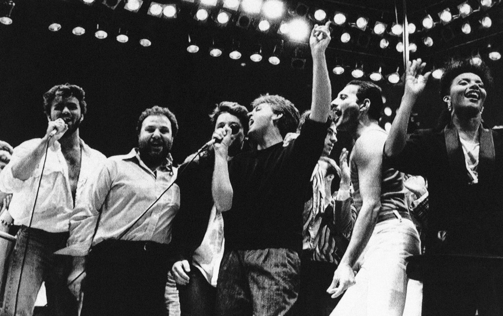 FILE - George Michael, from left, concert promoter Harvey Goldsmith, Bono, Paul McCartney, Bob Geldof, and Freddie Mercury appear during the London Live Aid Famine Relief Concert in London on July 13, 1985. (AP Photo/Joe Schaber, File)