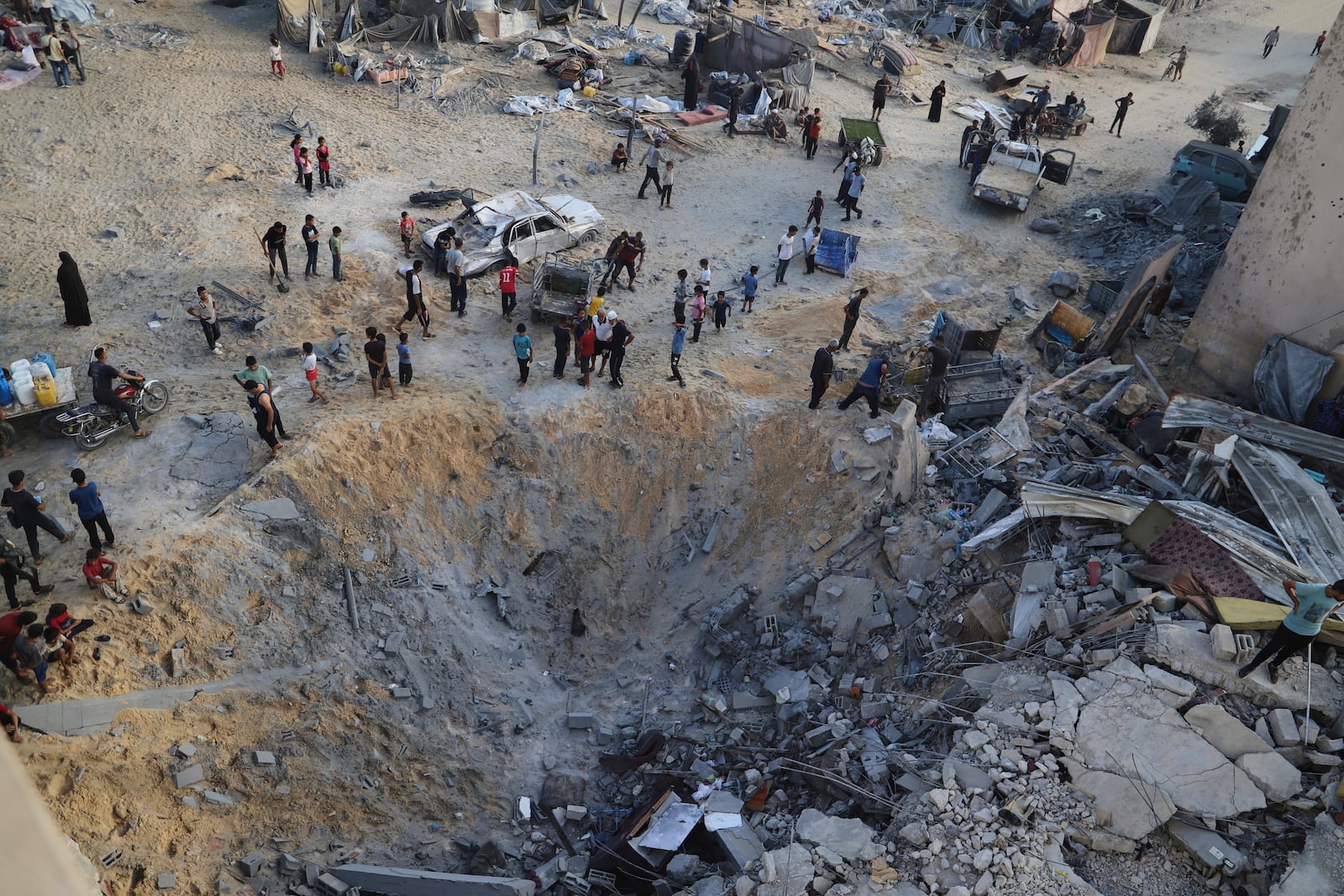 Palestinians inspect the site struck by an Israeli bombardment in Muwasi, Khan Younis, Gaza Strip, Monday, July 28, 2025. (AP Photo/Mariam Dagga)