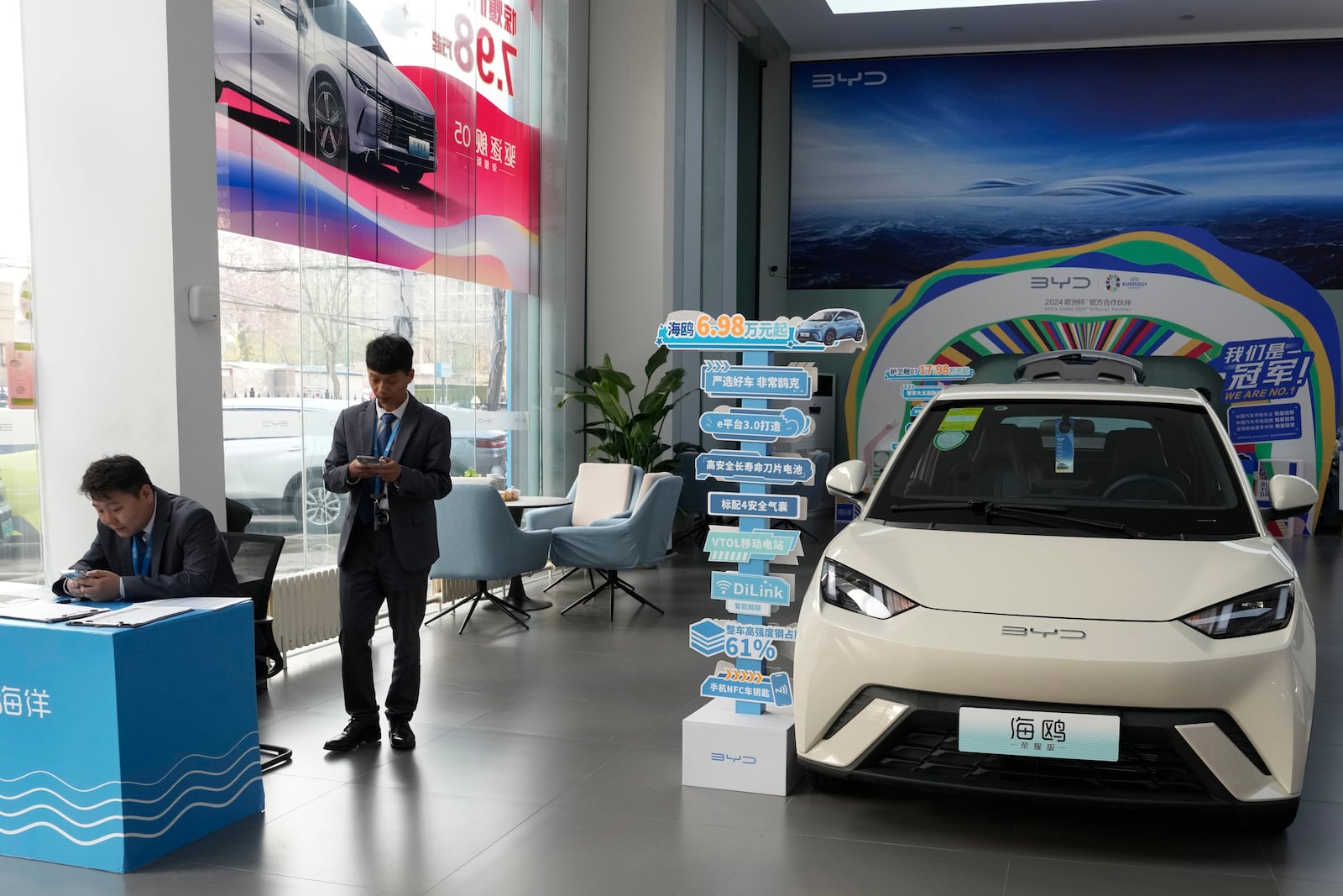 FILE - Sales staff stand near the Seagull electric vehicle from Chinese automaker BYD at a showroom in Beijing, Wednesday, April 10, 2024.(AP Photo/Ng Han Guan,File)