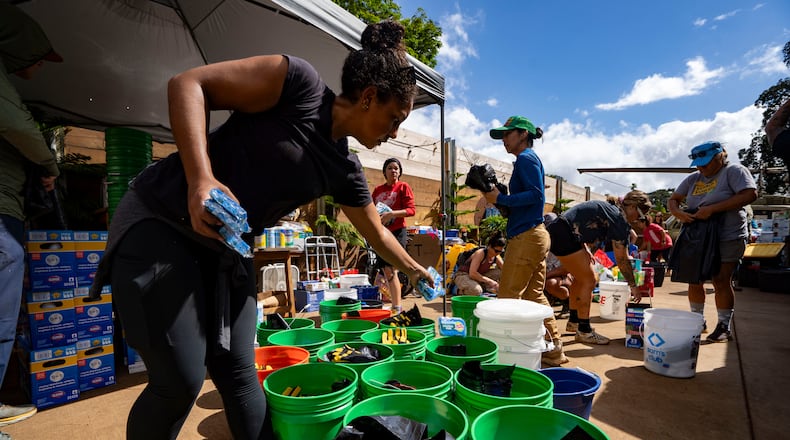 Volunteers sort donated supplies for distribution at Haleiwa Distillery following recent flooding, Tuesday, March 24, 2026, in Waialua, Hawaii. (AP Photo/Mengshin Lin)