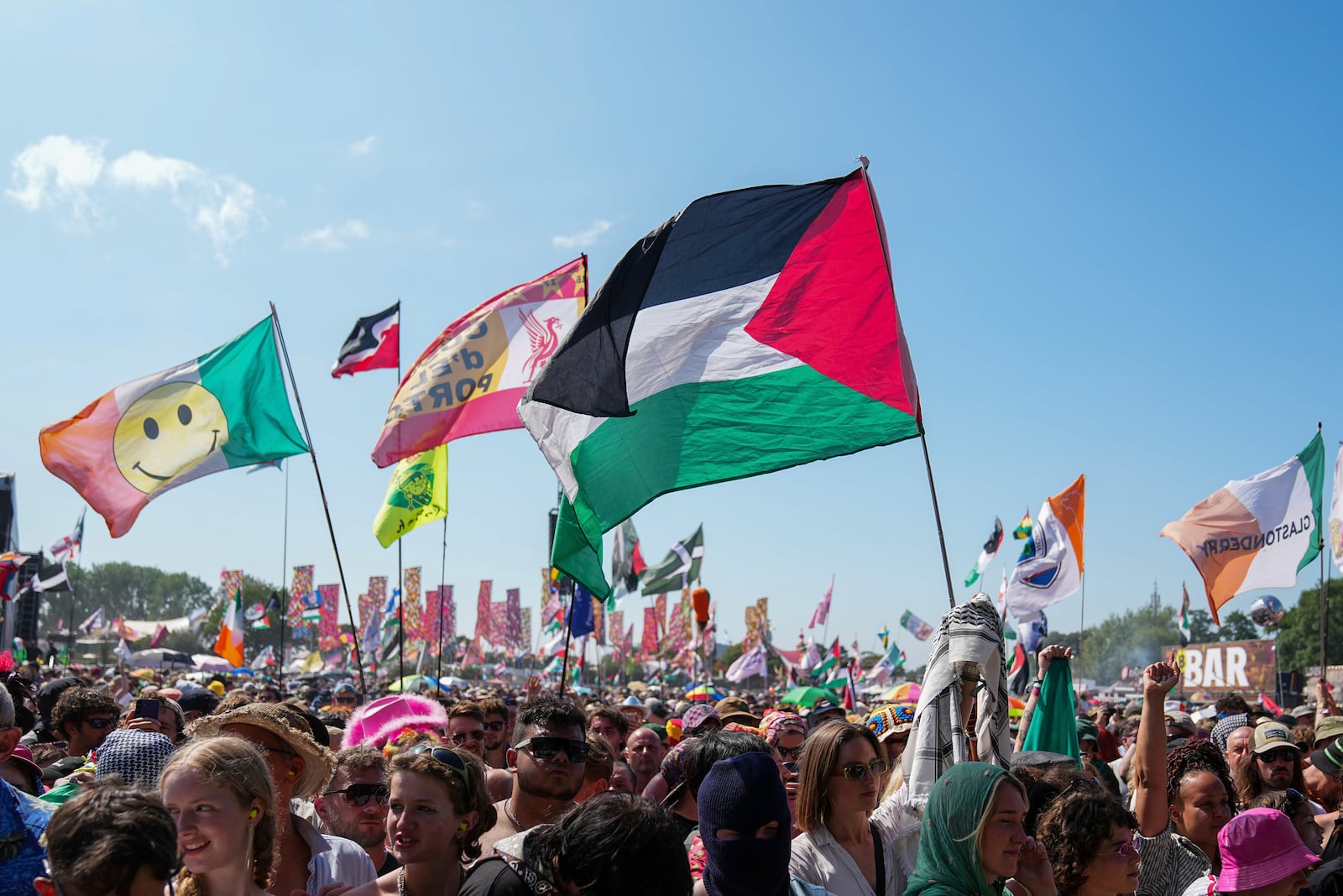 The flag of Palestine is waved in a crowd of festivalgoers at the hip hop trio Kneecap's performance during the Glastonbury Festival in Worthy Farm, Somerset, England, Saturday, June 28, 2025. (Scott A Garfitt/Invision/AP)