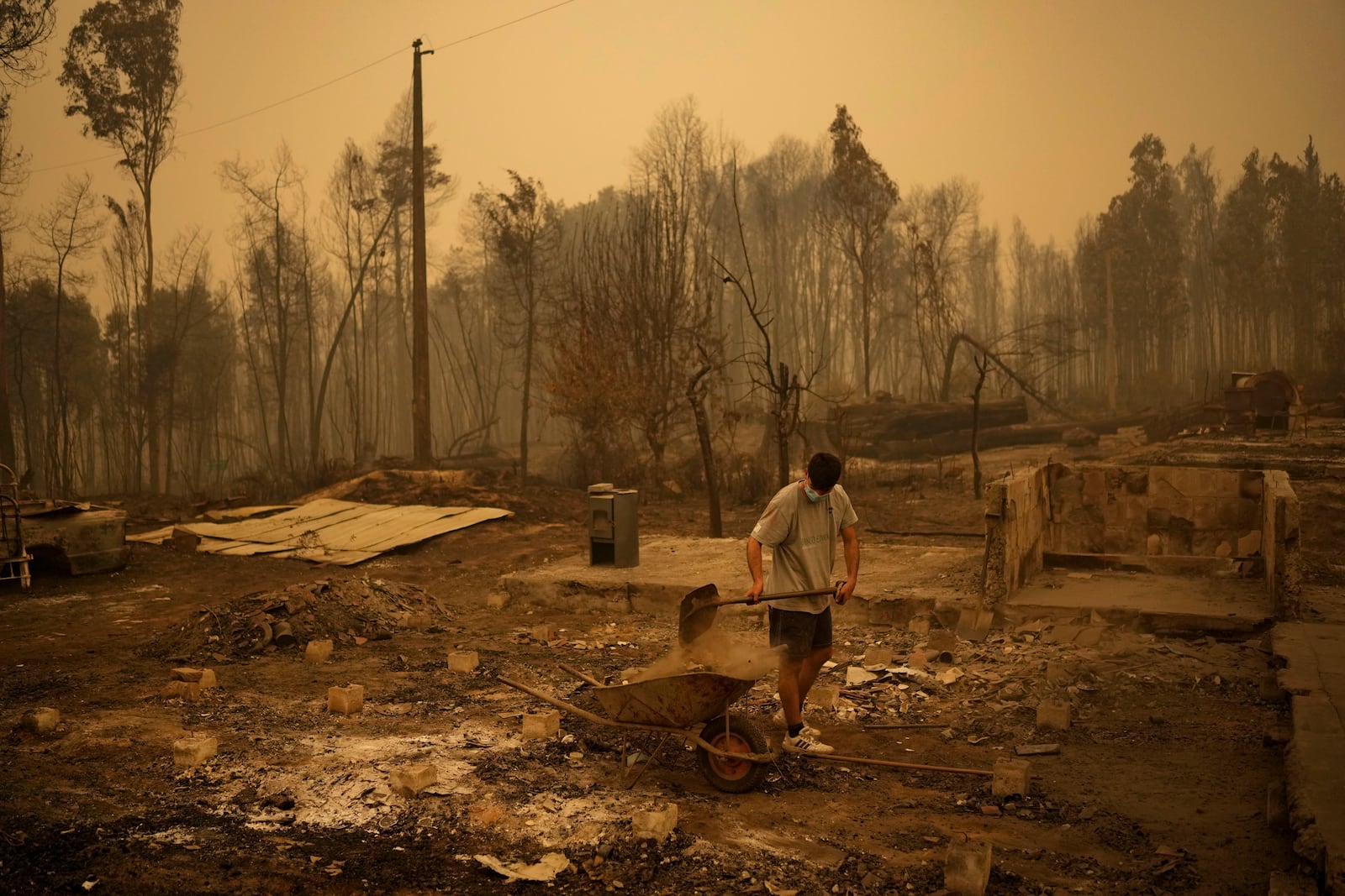 FILE - Yeremy Escanilla works on cleaning the debris of the remains of his house, destroyed by wildfires in Santa Juana, Chile, Feb. 5, 2023. (AP Photo/Matias Delacroix, File)