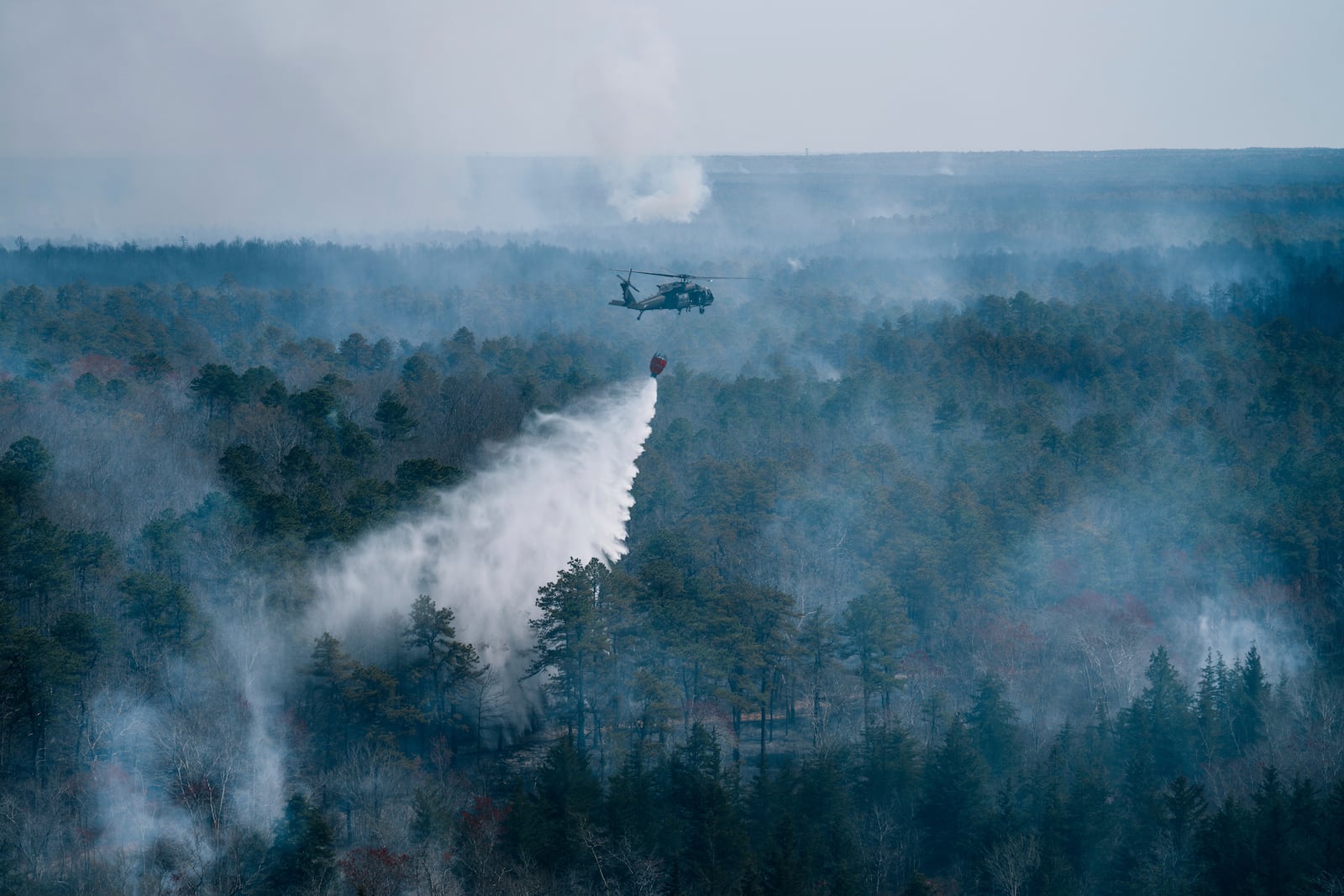 A helicopter drops water on a wildfire in Ocean County, N.J. on Thursday, April 24, 2025. (New Jersey Department of Environmental Protection via AP)