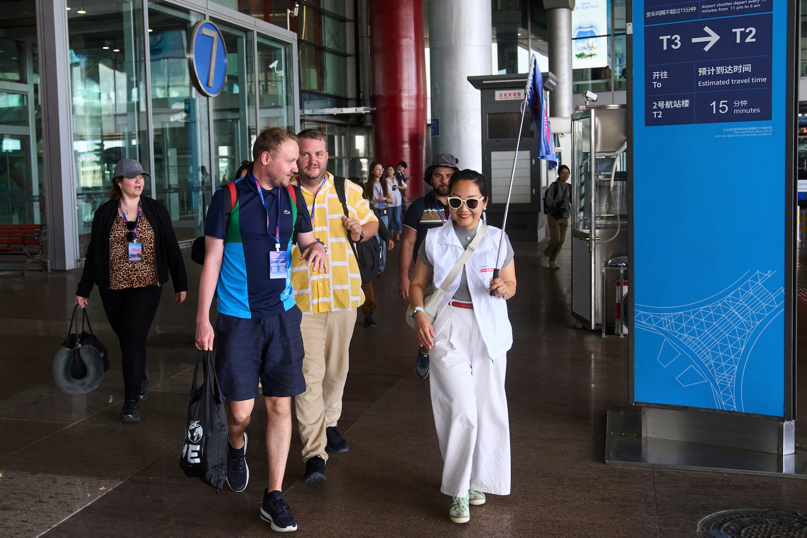 A tour guide leads tourists to the shutter bus to take a half-day tour to the tourism destination which offered by a travel agency Trip.com Group, at the Beijing Capital International Airport, in Beijing on June 15, 2025. (AP Photo/Andy Wong)