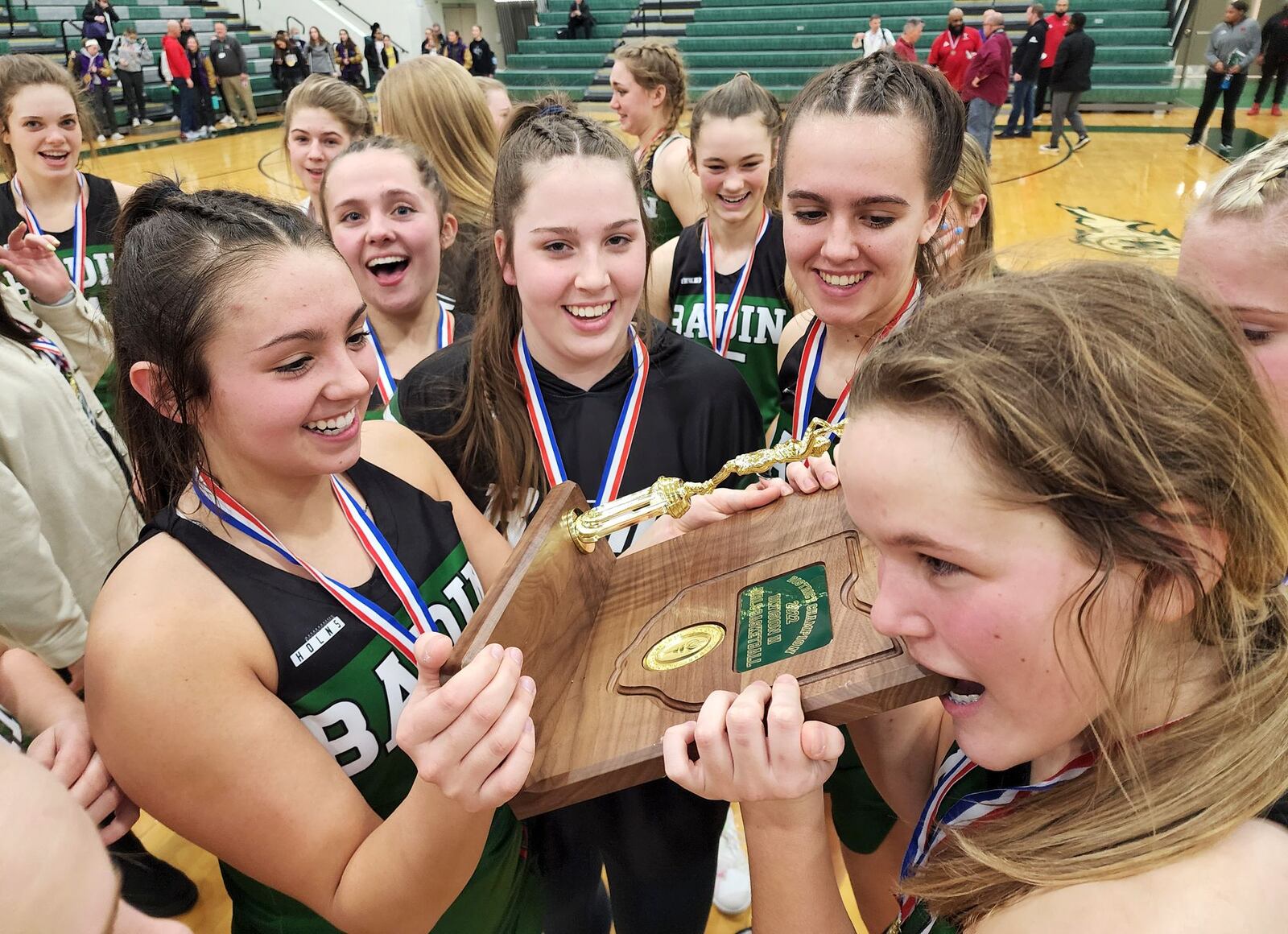 Mahya Lindesmirh, left, holds the district champion trophy as Katherine Beeber bites it after Badin defeated Trotwood-Madison 47-31 in their Division II district final basketball game Friday, Feb. 25, 2022 at Mason Middle School. NICK GRAHAM/STAFF