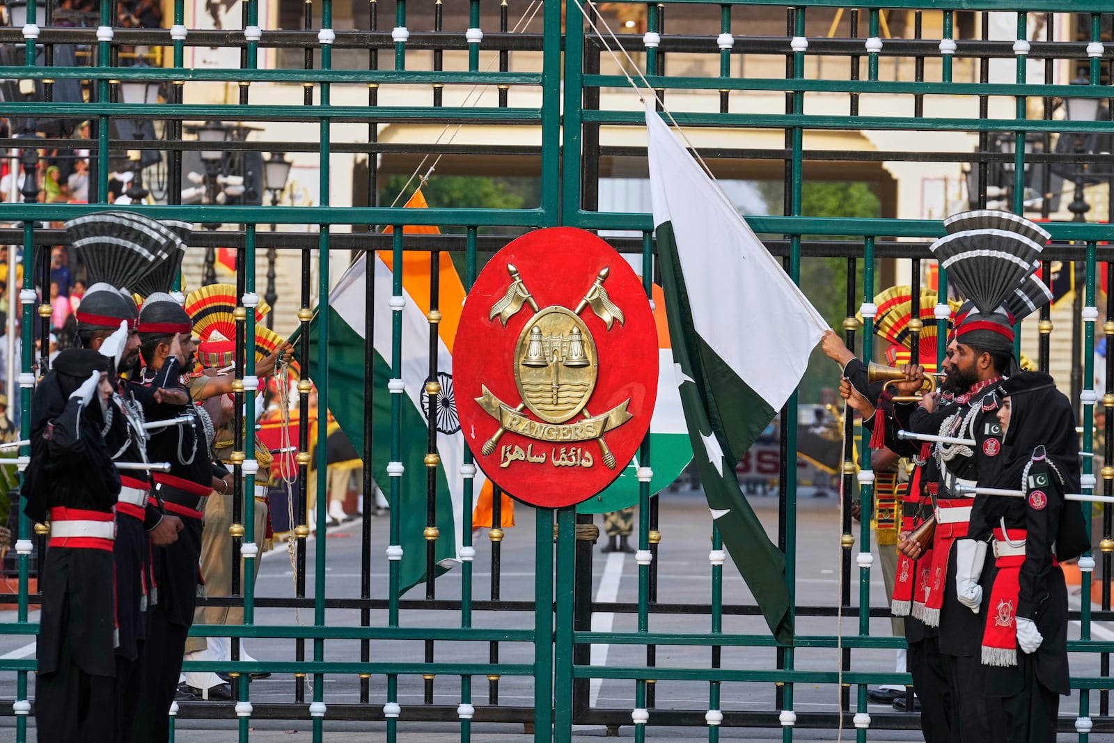 Pakistan's Rangers soldiers, in black, and Indian Border Security Forces soldiers, lower their flags during a daily closing ceremony at the Wagah, a joint post on the Pakistan and India border, near Lahore, Pakistan, Saturday, May 3, 2025. (AP Photo/K.M. Chaudary)