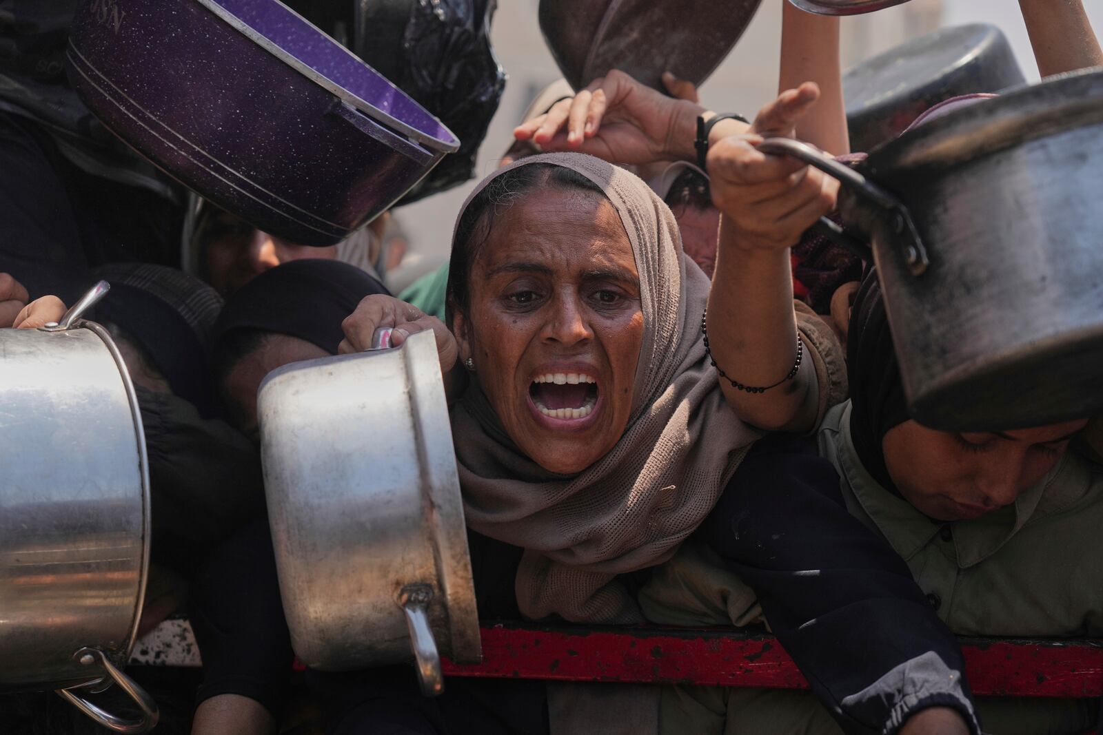 Palestinians struggle to get donated food at a community kitchen, in Gaza City, northern Gaza Strip, Saturday, July 26, 2025. (AP Photo/Abdel Kareem Hana)