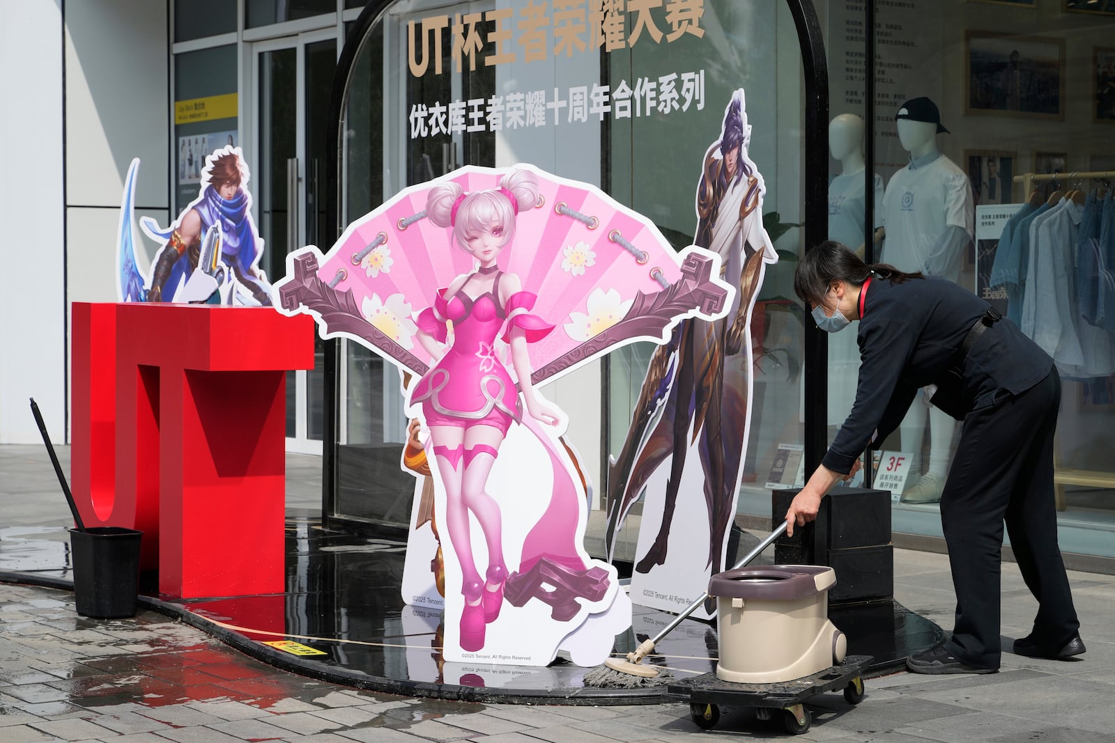 A worker wipes the ground near a promotion display at a mall in Beijing, Wednesday, May 7, 2025. (AP Photo/Ng Han Guan)