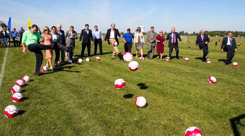 Dignitaries and special guests kick soccer balls as a group during a Grand Opening Ceremony and announcement revealing that West Chester Hospital and the MetroParks of Butler County have a new $1 million partnership to build a shelter house at the Voice Of America Park athletic complex that will house concessions, restrooms, trainer’s rooms, etc. The hospital is donating $1 million over 12 years and will provide sports medicine specialists and physical trainers at no costs to the athletes during tournaments. GREG LYNCH / STAFF