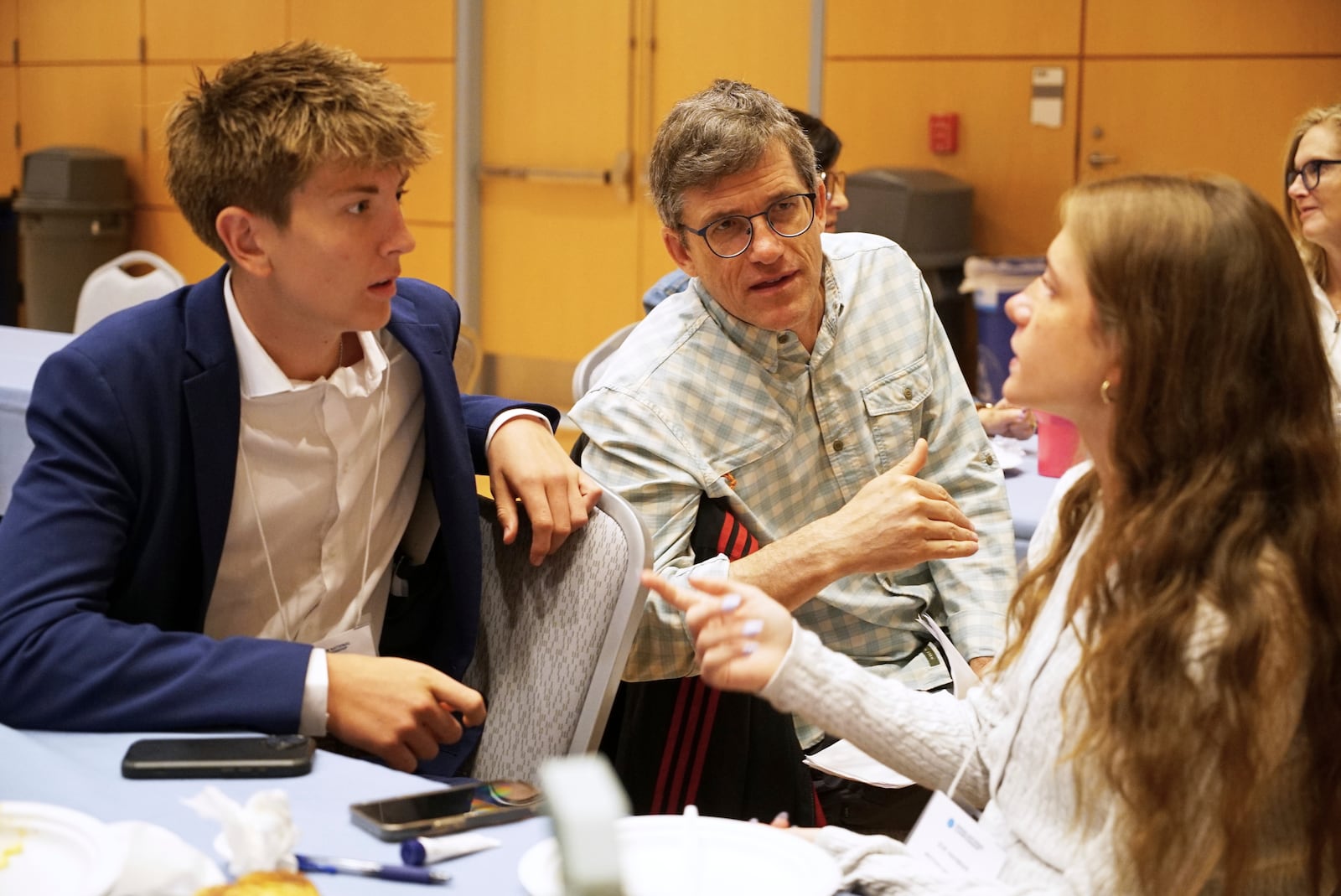 Midtown High School Ethics Bowl teammates Eric Snell, left, and Eve Nahmias speak with coach Eddy Nahmias, Eve's father, in between rounds of the National High School Ethics Bowl in Chapel Hill, N.C., on Sunday, April 13, 2025. (AP Photo/Allen G. Breed)