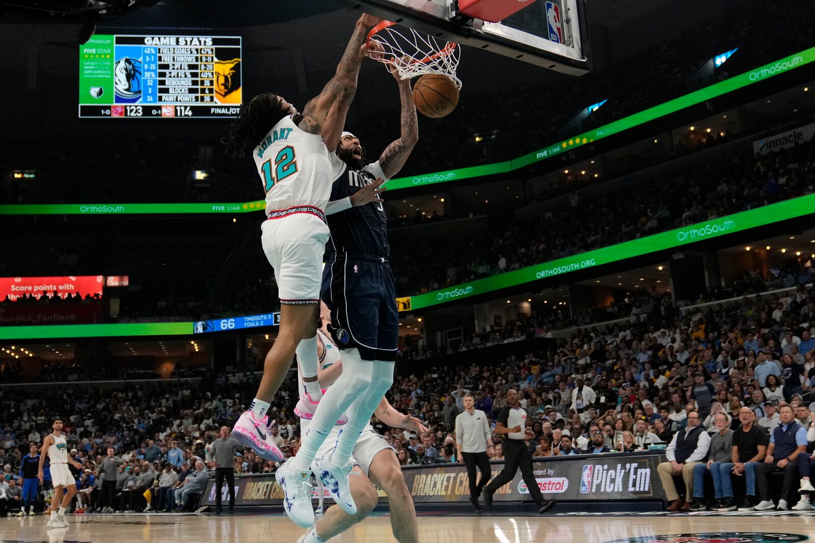 Dallas Mavericks forward Anthony Davis, right, dunks the ball past Memphis Grizzlies guard Ja Morant (12) during the second half of an NBA play-in tournament basketball game Friday, April 18, 2025, in Memphis, Tenn. (AP Photo/George Walker IV)