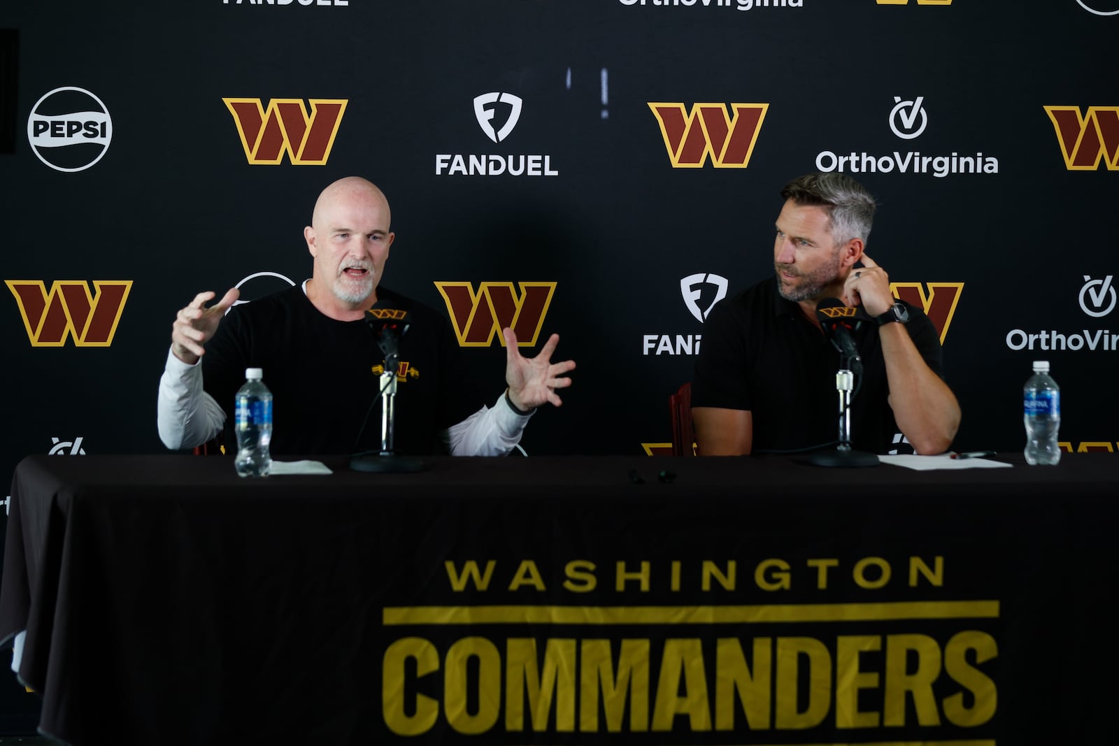 Washington Commanders head coach Dan Quinn, left, speaks as general manager Adam Peters, right, looks on during a news conference at the NFL football team's training camp in Ashburn, Va., Tuesday, July 22, 2025. (AP Photo/Luis M. Alvarez)