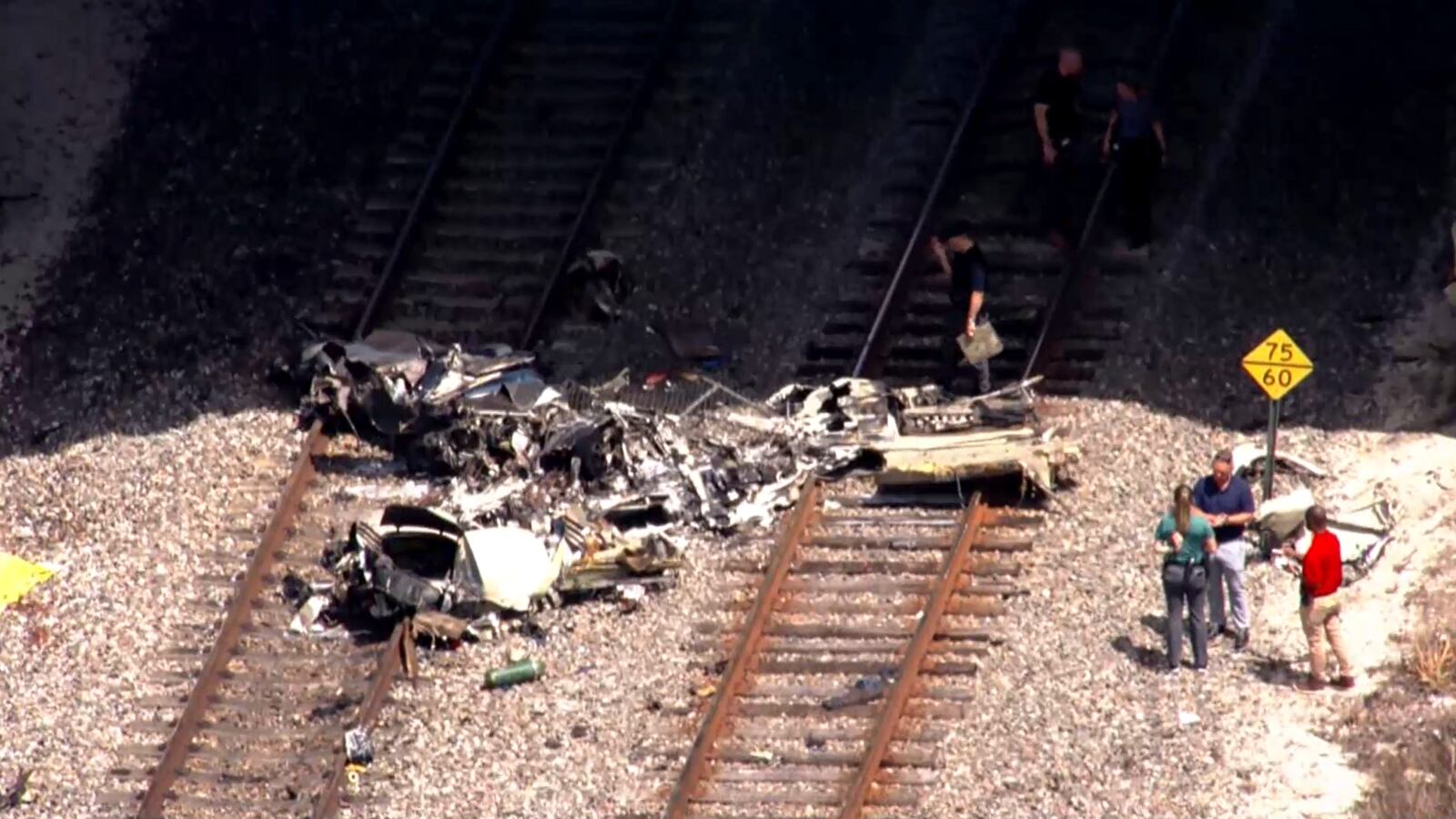 In this image taken from video provided by WSVN-TV, emergency personnel respond to the area where a small plane crashed on the railroad tracks beneath the overpass near Interstate 95 in Boca Raton, Fla., Friday, April 11, 2025. (WSVN-TV via AP)