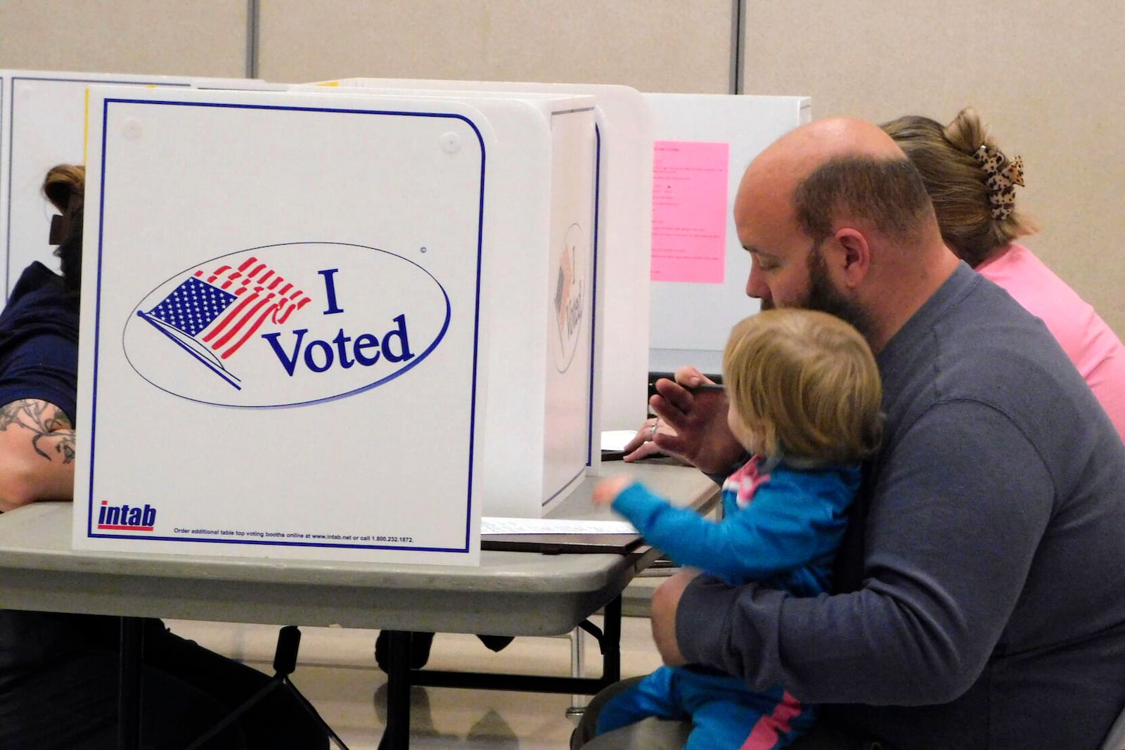 FILE - A man votes while holding a child at Valley View Elementary School Gym on Election Day, Nov. 5, 2024, in Rapid City, S.D. (Madison Willis/Rapid City Journal via AP, File)