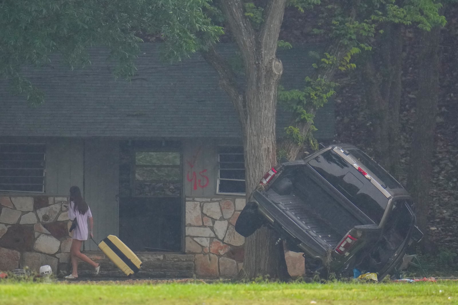 A person pulls luggage at Camp Mystic along the banks of the Guadalupe River after a flash flood swept through the area Sunday, July 6, 2025, in Hunt, Texas. (AP Photo/Julio Cortez)