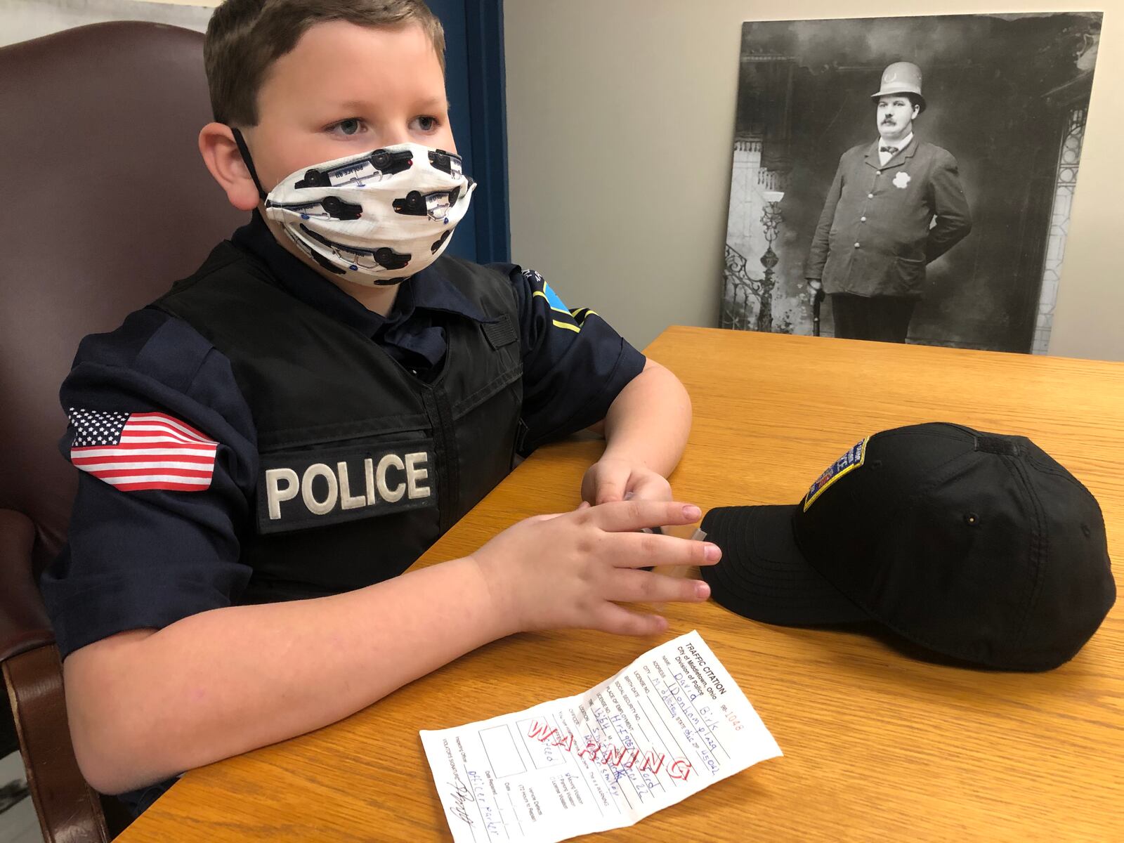 Parker Smiley, 9, served as a Middletown police officer for a day and part of his responsibilities was pulling over Chief David Birk for speeding. Parker gave the chief a warning and he kept a copy of the ticket. RICK McCRABB/STAFF
