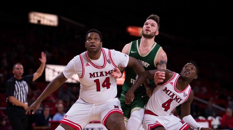 Miami’s Bam Bowman (14) and Isaiah Coleman-Lands (4) block out Wright State’s Bill Wampler during a game earlier this season. Miami defeated Wilberforce on Monday afternoon at Millett Hall. FILE PHOTO