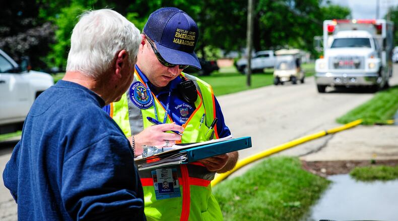 Ron Crysel, left, talks in May 2017 to Greg Brooks with Butler County Emergency Management Agency to survey damage to his home after flood waters filled the basement and lower level on East Ritter Street in Seven Mile. NICK GRAHAM/FILE