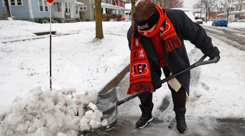 Donna Hall, a diehard Bengals fan, was showing support for her team as she cleaned the slush off Northern Avenue in front of her house so her husband, who works third shift, could have a clean place to park Wednesday morning Jan. 25, 2023, in Springfield. BILL LACKEY/STAFF